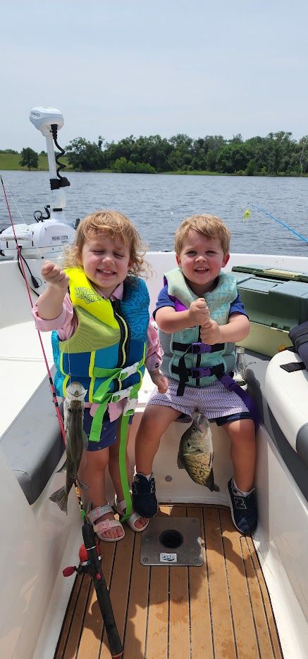 Two young anglers holding their catch on the boat